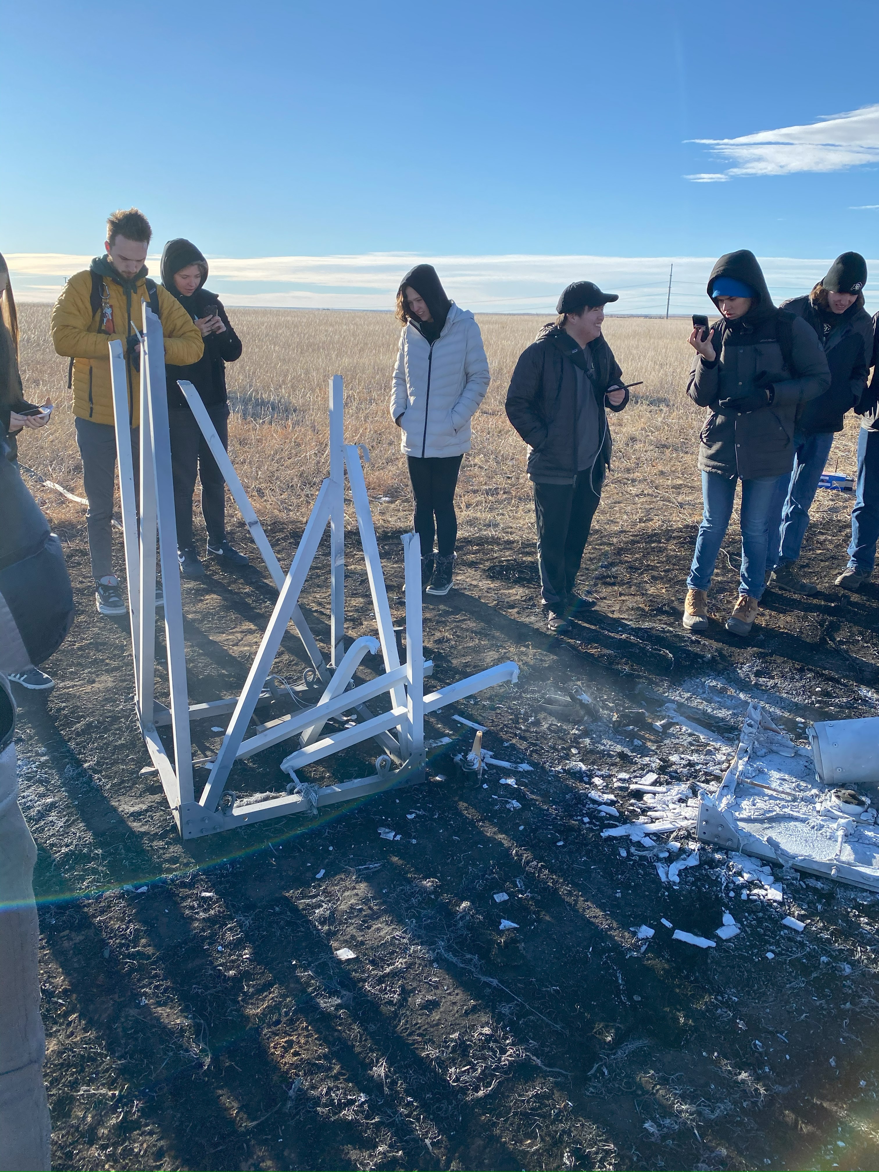 Team gathered around the melted test stand with aluminum oxide residue
